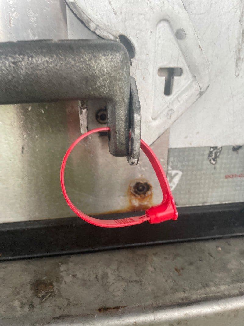 Red plastic seal threaded through the trailer door latch